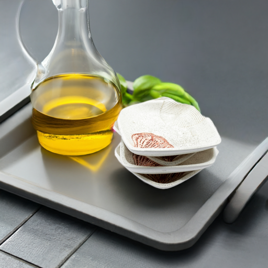 A white ceramic dipping plate with a garlic print design sits on a black serving platter. Next to it, a fresh loaf of bread rests on a wooden cutting board.